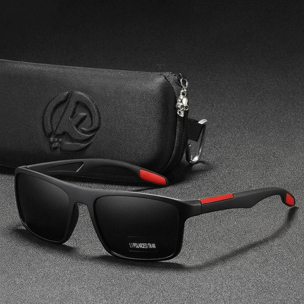 Black sunglasses with red accents on a gray surface with a black pouch in the background.
