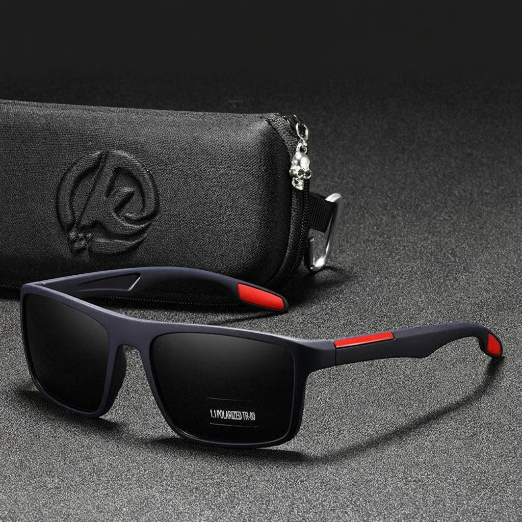 Black sunglasses with red accents on a gray surface with a black case in the background.