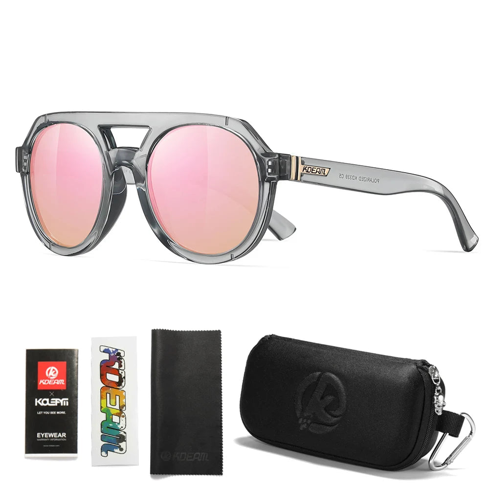 Transparent gray sunglasses with mirrored pink lenses, accompanied by a case and cleaning cloth on a white background.