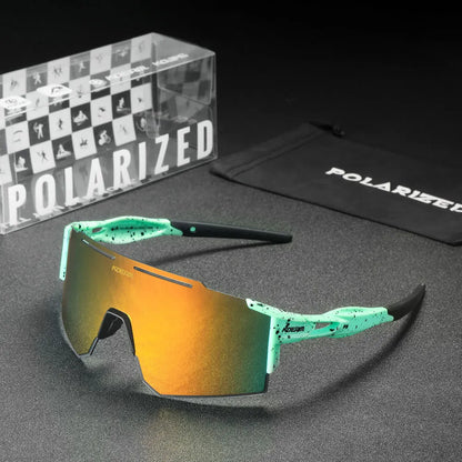 Polarized sunglasses with green frame and orange lens on a gray surface, accompanied by a branded case and packaging.