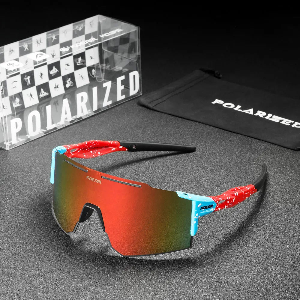 Polarized sunglasses with red and blue frame on a gray surface, accompanied by a branded box and pouch.